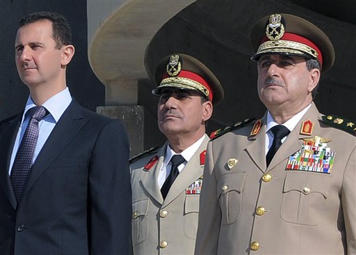 Syrian President Bashar Assad, left, stands next to then-Defense Minister Gen. Dawoud Rajha, right, during an Oct. 6, 2011, ceremony in Damascus. Rajha was killed in a suicide attack on July 18, 2012. The man at right is unidentified.
