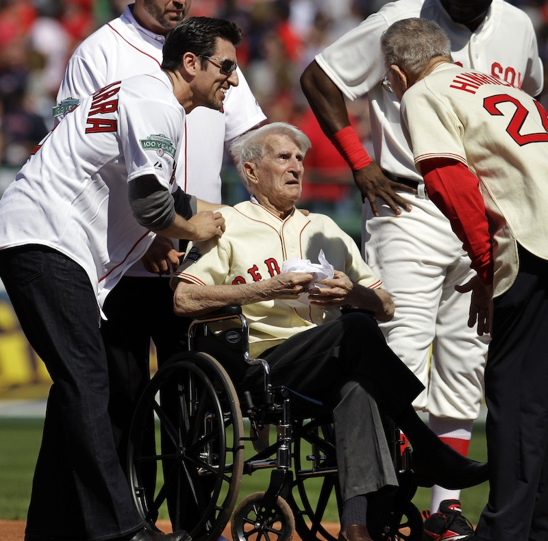 In this April 20, 2012, file photo, Boston Red Sox great Johnny Pesky, center, is greeted by former player Nomar Garciaparra, left, and others during a celebration of the 100th anniversary of the first regular-season baseball game at Fenway Park prior to the Red Sox taking on the New York Yankees in Boston. Pesky, who spent most of his 60-plus years in pro baseball with the Red Sox and was beloved by the team's fans, has died on Monday, Aug. 13, in Danvers, Mass. He was 92. (AP Photo/Elise Amendola, File)