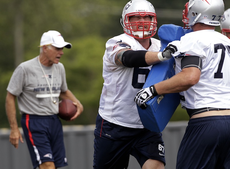 Coming of off a season-ending injury last year, New England Patriots center Dan Koppen (67) works a blocking drill against tackle Nate Solder (77) as assistant head coach and offensive line coach Dante Scarnecchia, left, shouts orders at practice during NFL football training camp in Foxborough, Mass., Thursday, Aug. 2, 2012. (AP Photo/Stephan Savoia)