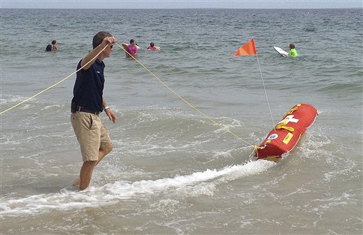 Misquamicut, R.I., Fire Chief Louis Misto, left, holds a line attached to the EMILY remote-control lifesaving device as it propels itself in the water and away from the shore at Old Town Beach, in Westerly, R.I.