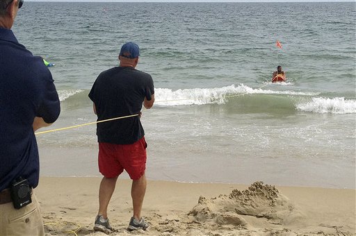 Fire Chief Louis Misto, far left, and lifeguard Jeff Lenihan, center, demonstrate a rescue technique with the EMILY remote-control lifesaving device as lifeguard Philip Campo, in water at right, holds on to the apparatus at Old Town Beach, in Westerly, R.I.