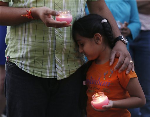 A man holds his child during a candle light vigil for the victims of the Sikh Temple of Wisconsin shooting in Milwaukee Sunday. An unidentified gunman killed six people at the suburban Milwaukee temple on Sunday in a rampage that left terrified congregants hiding in closets and others texting friends outside for help.