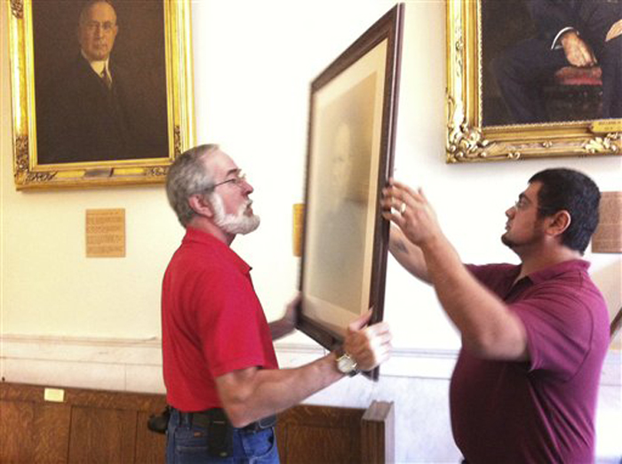 In this still image from video provided by WMUR-TV, workers on Wednesday remove a portrait purported to be former Gov. Henry Keyes.