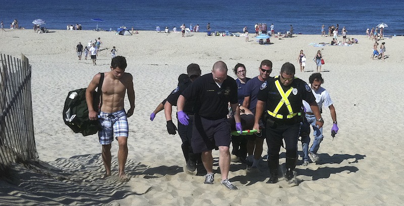 In this Monday, July 30, 2012 photo, Christopher Myers is carried off Ballston Beach in Truro, Mass., after sustaining shark-bite wounds to his legs while swimming. (AP Photo/Cape Cod Times, Eric Williams)