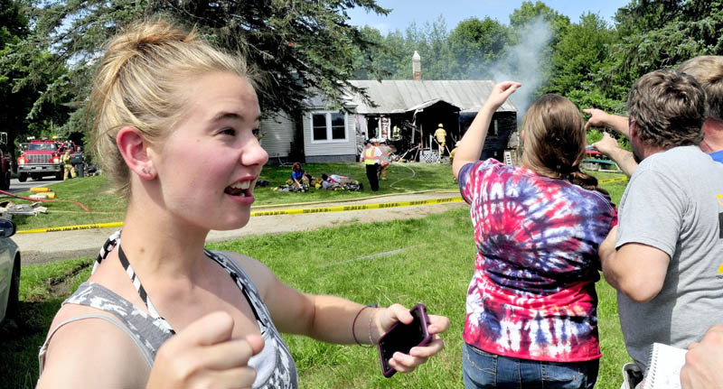 Babysitter Amanda Garboski recounts her reaction after discovering fire in this home on the Smithfield Road in Belgrade on Monday. Angelia and Kevin Tozier point as firefighters extinguish the stubborn blaze. Garboski got two children and a dog out safely.