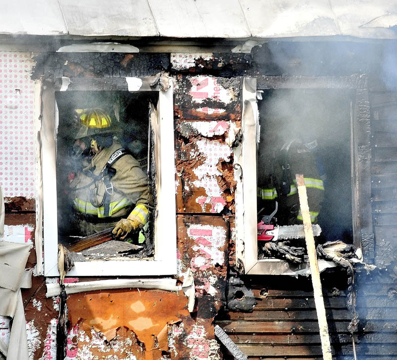 Staff photo by David Leaming SERIOUS DAMAGE: Firefighters search for fire inside a home that caused serious damage to the building on the Smithfield Road in Belgrade on Monday.