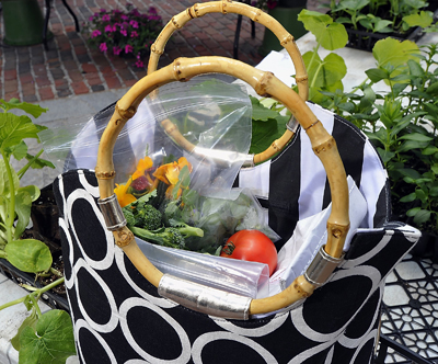 A shopper at the Monument Square Farmers Market filled her shopping bag with edible flowers, herbs, greens, broccoli, stone milled flour and fresh tomatoes.