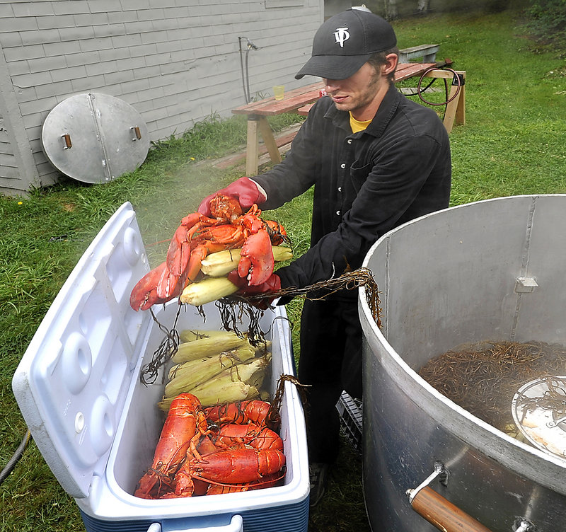 Maine Lobsterbake head chef Jim Dinsmore loads the food into an insulated container to keep warm until dinner is served.