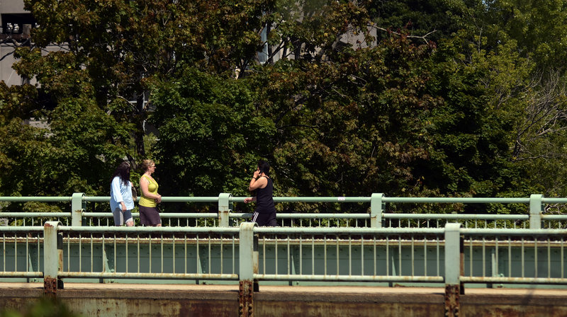 Pedestrians cross the Presumpscot River on Bridge Street in Westbrook on Monday. The bridge carries 12,000 to 13,000 cars a day and is popular with pedestrians.