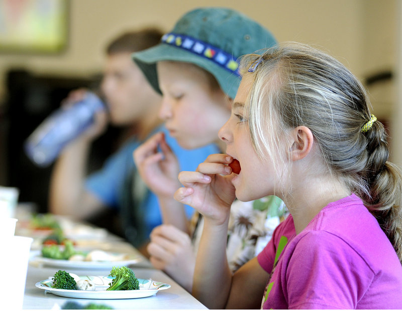 Tamisa Ferrente, 7, samples a tomato during a CATCH Healthy Habits program at the South Portland Boys & Girls Club recently. The nutrition and exercise lessons include teaching the children to identify “go” foods, “slow” foods and “whoa” foods, “go” being the healthiest and “whoa” the least.