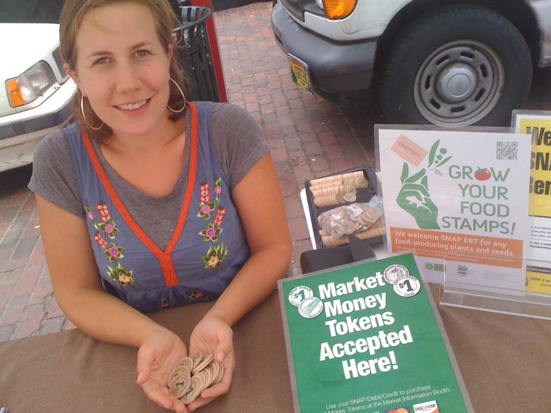 Dani Scherer, SNAP program staffer at the Portland Farmers Market, holds wooden tokens that food stamp recipients and credit and debit card users can obtain at the market information booth. The grant funding to support Scherer’s position at the Wednesday and Saturday markets and pay for the electronic processing equipment and fees runs out at the end of August.