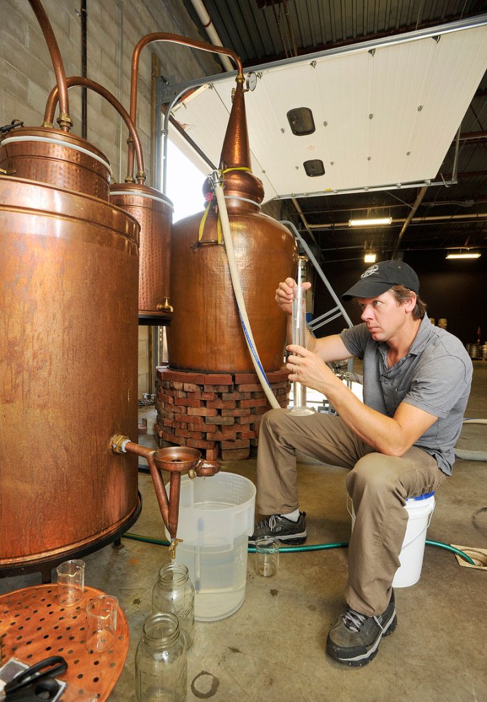Distiller Tim Fisher uses a hydrometer to measure the alcohol content of rum coming out of New England Distilling’s copper still, which was made in Portugal, and which Wight designed himself.