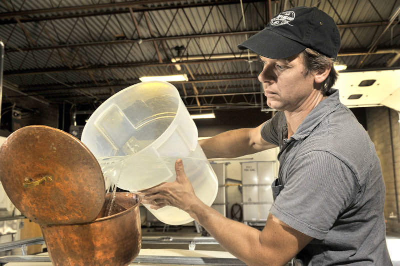 Tim Fisher pours recently distilled rum into a holding tank.
