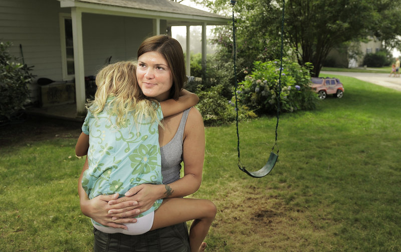 Laura Anderson holds her daughter, Grace, 7, outside their Lawson Road home in Cape Elizabeth. Anderson says she hasn’t noticed excessive noise in the area related to nearby short-term rental properties.