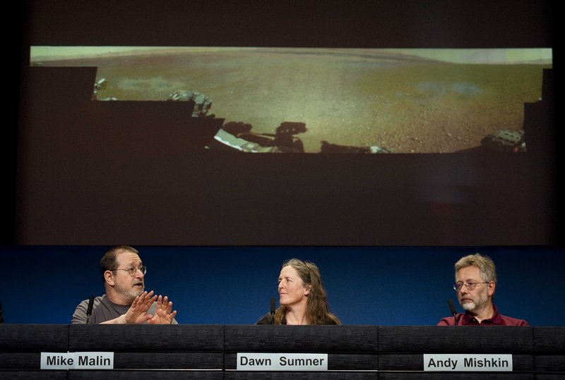 Michael Malin of Malin Space Science Systems, San Diego, left, talks next to Dawn Sumner, University of California, Davis, and Andy Mishkin of NASA’s Jet Propulsion Laboratory, about a low-resolution panoramic image of Mars, background, during a news conference Thursday.