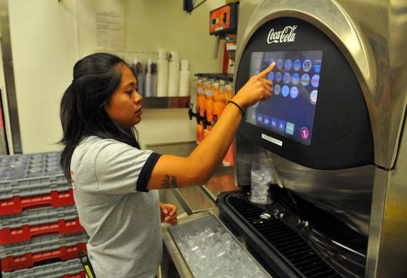 Junabelle Devega, a server at a Taco Mac in Sandy Springs, Ga., uses a Coca-Cola Freestyle fountain dispenser. The computerized drink machines dispense combinations of more than 120 of the company’s brands.