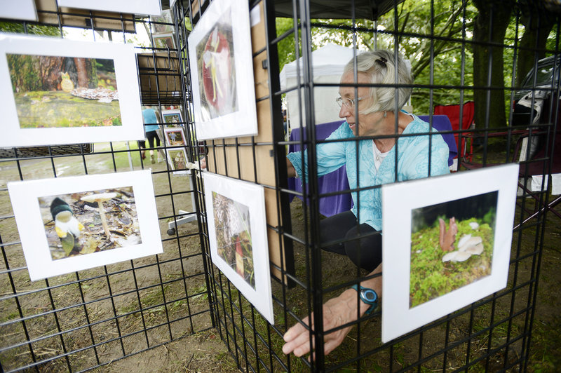 Artist Arabella Eldredge of Cumberland wipes down her display after a rain shower during Art in the Park at Mill Creek Park in South Portland on Sunday.