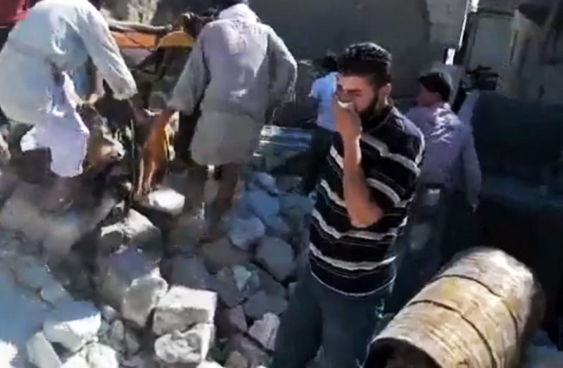 Image made from amateur video accessed Sunday purports to show a Syrian man reacting after other men, left, lifted a body from the rubble of a building destroyed by Syrian forces shelling Kfarnebel, in Idlib province, northern Syria.