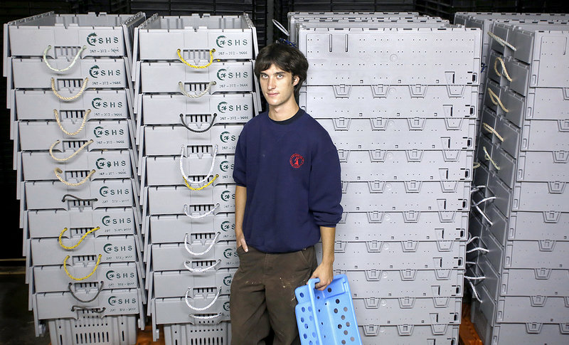 Kyle Murdock stands in front of lobster crates at the new plant.