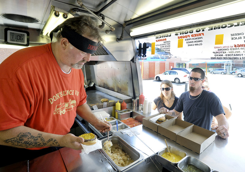 Jim Richards puts onions on a cheeseburger for Sean Bearor of Limerick on Tuesday. Bearor and his wife, Jessica, try to eat at Don’s whenever they drive through Westbrook. “If it’s open, we stop,” he said.