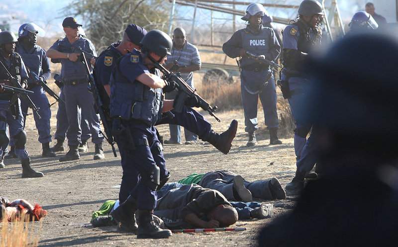 Police surround the bodies of striking miners after opening fire on a crowd Thursday at the Lonmin Platinum Mine near Rustenburg, South Africa. Up to 18 people were killed.