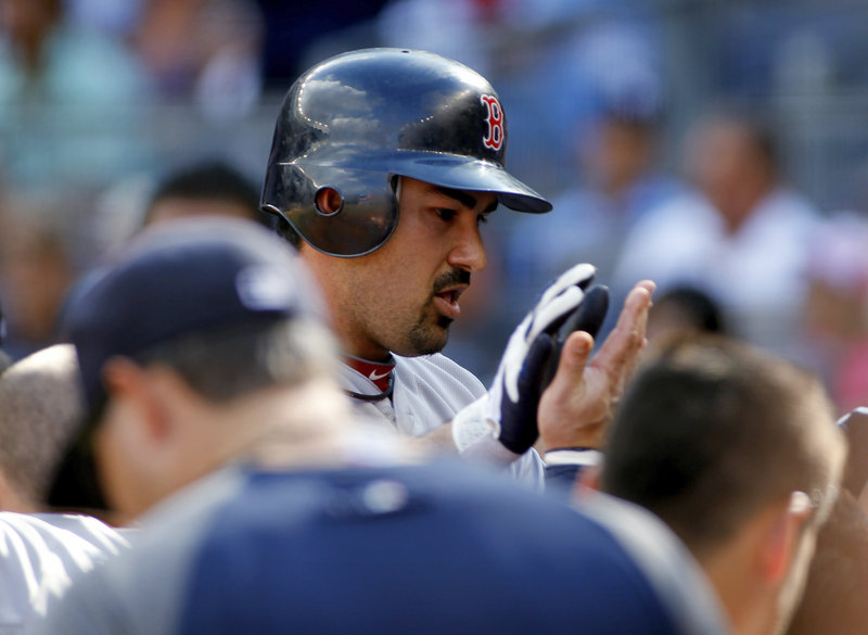 Adrian Gonzalez is welcomed back to the dugout by Red Sox teammates after hitting a two-run homer off David Phelps of the Yankees in the first inning.