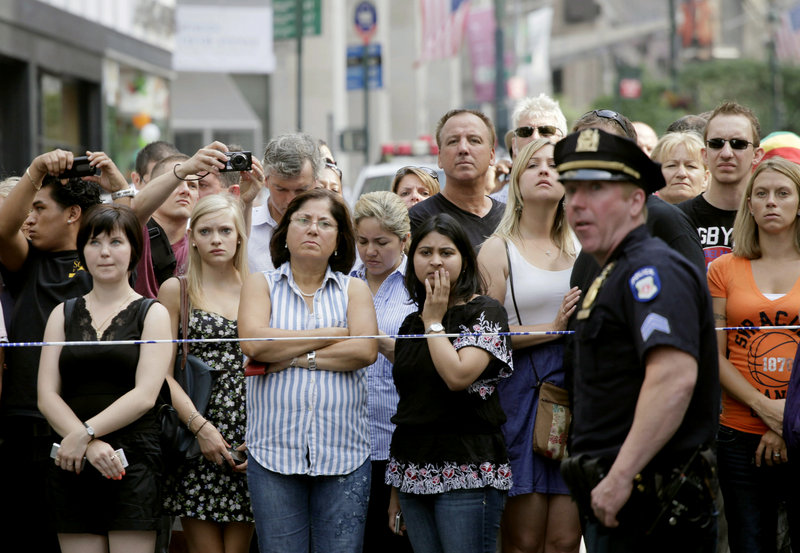 Bystanders and a police officer stand on Fifth Avenue after a shooting outside the Empire State Building in New York on Friday. One man and the gunman died, and nine others were wounded. A law enforcement official said the shooting was related to a workplace dispute.