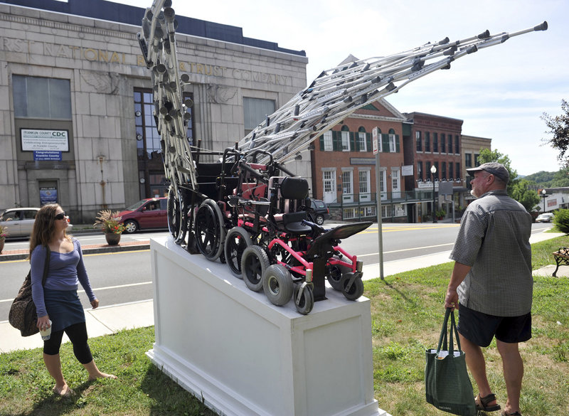 Daniel Turner takes a look at a sculpture by James Kitchen on display on the Town Common in Greenfield, Mass. The sculpture will be moved to Springfield in September.