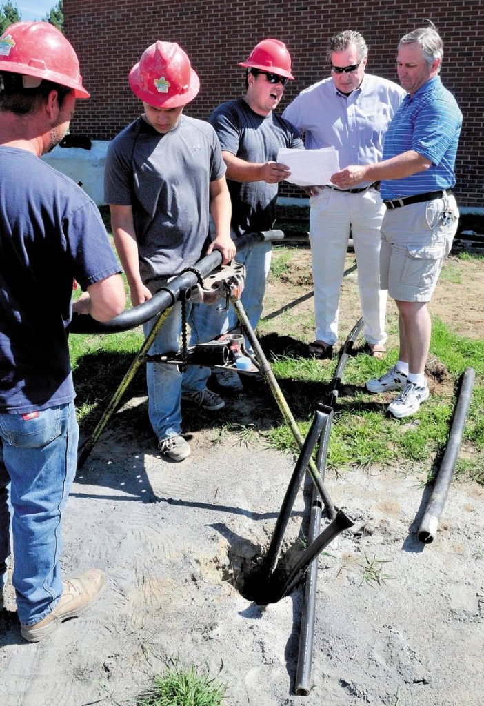 Grignon, center, explains the system being installed at the school to Superintendent Todd LeRoy and Principal Steve Ouellette last week, while Alan Grill, left, and Antoine Grignon install the piping system.