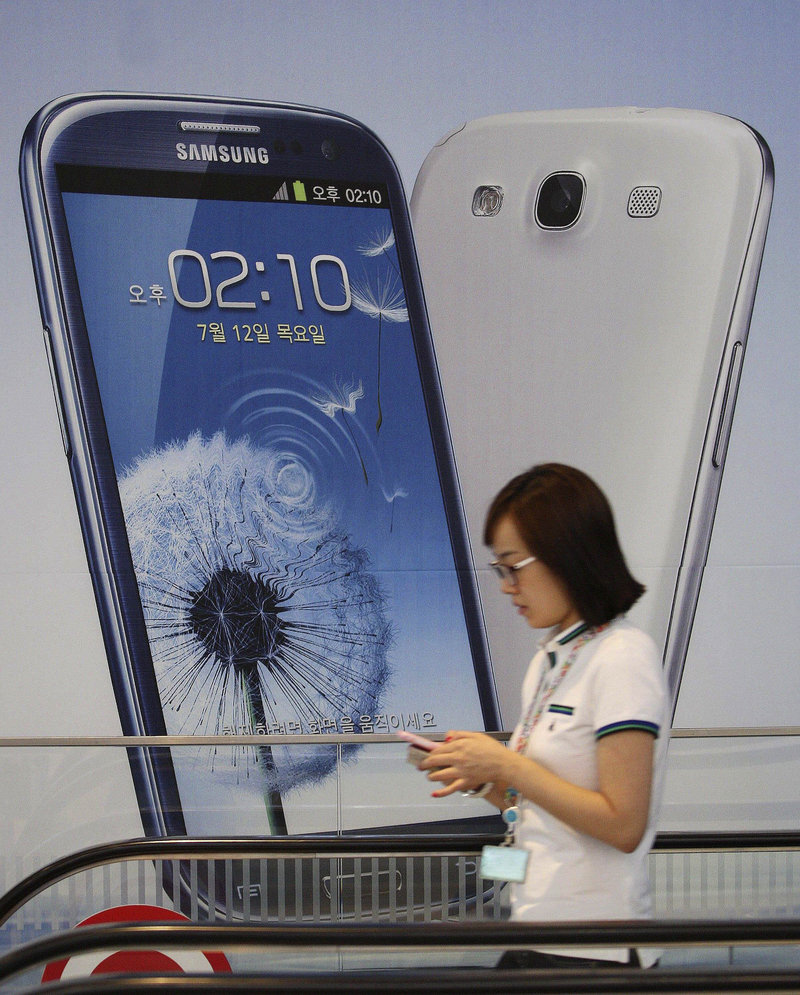A woman walks by a sign advertising Samsung’s mobile phone Galaxy III at the company’s headquarters in Seoul.