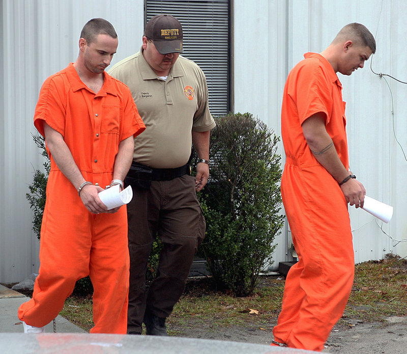 In this Dec. 12, 2011, file photo, Army Pfc. Michael Burnett, 26, right, and Pvt. Christopher Salmon, 25, are led away in handcuffs after appearing before a magistrate judge at the Long County Sheriff's Office in Ludowici, Ga.