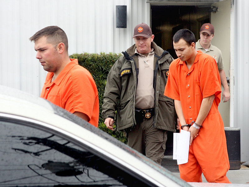 In this Dec. 12, 2011, file photo, Army Sgt. Anthony Peden, 25, left, and Pvt. Isaac Aguigui, 19, are led away in handcuffs after appearing before a magistrate judge at the Long County Sheriff's Office in Ludowici, Ga.