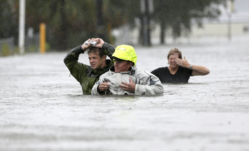 Chuck Cropp, center, his son Piers, left, and wife, Liz, wade through floodwaters from Hurricane Isaac Wednesday in New Orleans.