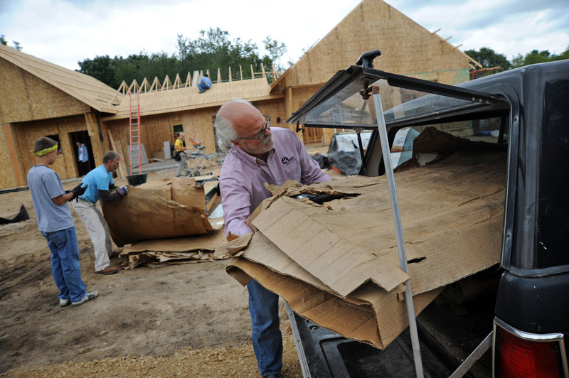 Kelly Cain, director of the St. Croix Institute for Sustainable Community Development, loads cardboard from the construction site in Eco-Village to be shredded for garden mulch in the high-efficiency residential development.