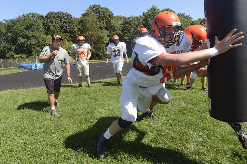 Biddeford football coach Scott Descoteaux looks on as linemen, including Kevin Descoteaux, go through a drill in practice. Biddeford was winless last season and there was concern it influenced a decision to drop to Class B. But enrollment was the factor, and the Tigers will stay in Class A.