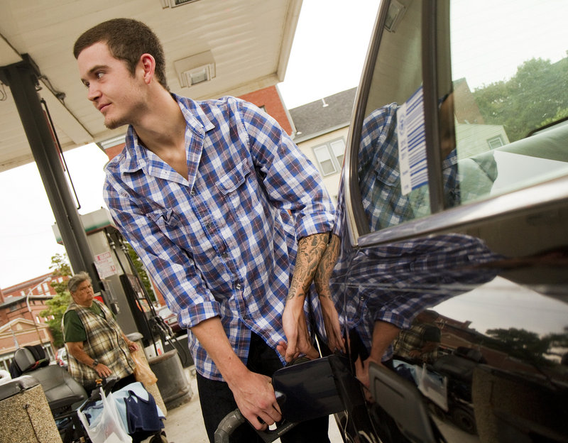 Dylan McIntyre of West Falmouth fills up his 20-year-old BMW at a Congress Street gas station in Portland on Friday. “I’m not too worried,” he said, shrugging off the price fluctuations even though he acknowledged that his car gets pretty abominable gas mileage.