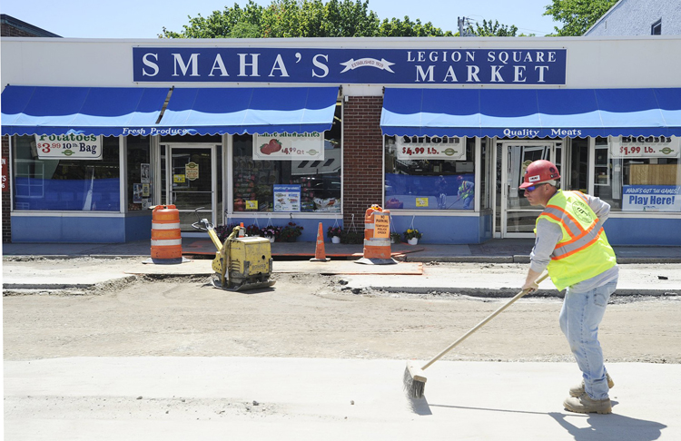 Mike Stuart of Shaw Brothers Construction sweeps the street in front of Smaha's Legion Square Market in this June 14, 2012 photo.