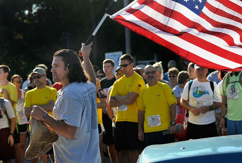 Carlos Arredondo of Boston waves the starting flag, while holding the boots of his late son Lance Cpl. Alexander Arredondo, at the Run for the Fallen in Ogunquit on Sunday. His son died while serving in the Marine Corps in Iraq in 2004.
