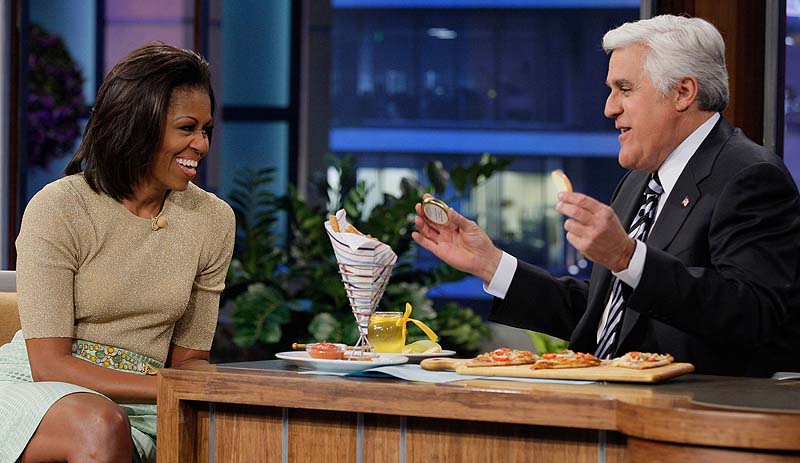 Tonight Show host Jay Leno, speaking with first lady Michelle Obama in January, will be taking a severe pay cut to stave the jobs of his staffers. NUP_148189_0120.jpg;2010s; 2011-2012; Air Date 01/31/2012; Color
