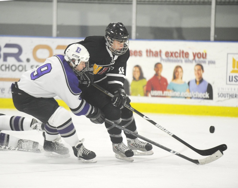 In this January 2010 file photo, former Deering High School player A.J. Asbury, No. 9, left, pressures the puck. Deering High School has received a waiver to merge its boys' hockey team with Portland High School's team.