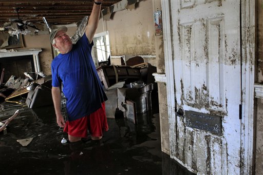 Don Duplantier walks through his flooded home as water recedes from Hurricane Isaac in Braithwaite, La., Sunday, Sept. 2, 2012. In the foreground is a sign marking the waterline from Hurricane Katrina, but floodwater from Isaac went all the way to the second floor. More than 200,000 people across Louisiana still didn't have any power five days after Hurricane Isaac ravaged the state. Thousands of evacuees remained at shelters or bunked with friends or relatives. (AP Photo/Gerald Herbert)