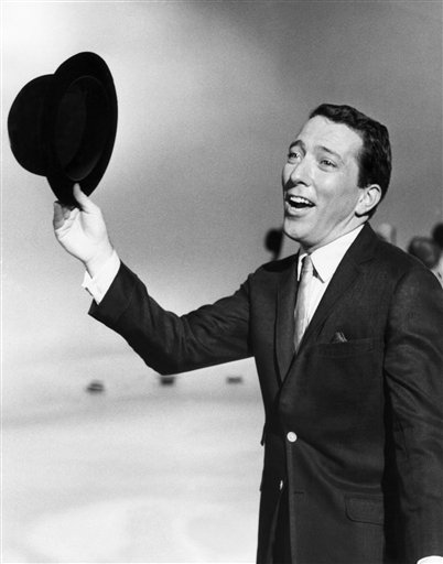 FILE - In a May 12, 1961 file photo, Andy Williams performs a song on a television show. Emmy-winning TV host and "Moon River" crooner Williams died Tuesday night, Sept, 25, 2012 at his home in Branson, Mo., following a year-long battle with bladder cancer. He was 84. (AP Photo, File) Singing Singer Holding Hat Looking Away Performance Standing