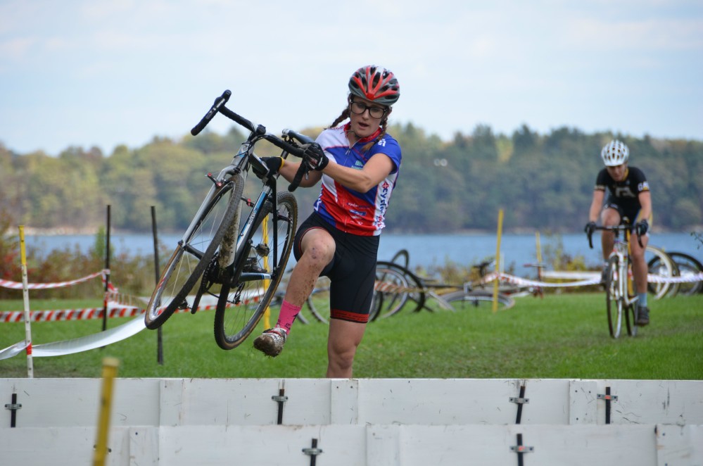 Ellen Noble of Kennebunk carries her bike as she leaps a barrier during last year's Casco Bay Cyclocross women's event. Paul Weiss photo