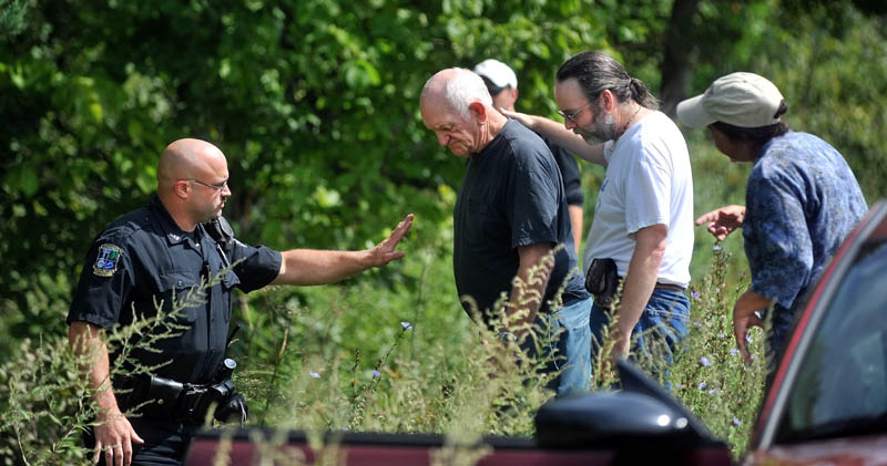 Waterville police officer Steve Brame, left, gestures for Horace Crawford, center, to wait on the road for paramedics. John McCuthon, center right, comforts Crawford. McCutchon was traveling in the opposite direction and witnessed Crawford go off the road.