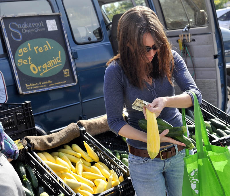 Kassandra Weese of Albion selects some cucumbers and squash from the Snakeroot Organic Farm stand at the Waterville farmers market at The Concourse on Thursday afternoon. “I buy organic food for two reasons: to avoid pesticides and buy locally,” she said.