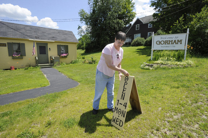 In this July 11, 2012, photo, Ellen Bessey, daughter of former librarian Lorraine Jonassen, sets out the open sign for the last time before the closing of the South Windham Library due to lack of customers.
