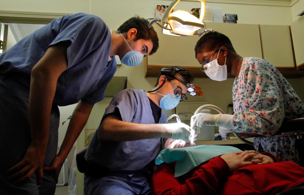A dentist fills a tooth for a patient during a free clinic in 2009. A proposed rule change approved by the state dental board would deny access to public health dental clinics to children who had seen a dentist in the past 12 months. Instead of being able to treat the child, the clinic would have to get clearance from the dentist, whether the child is a regular patient in the practice or not.