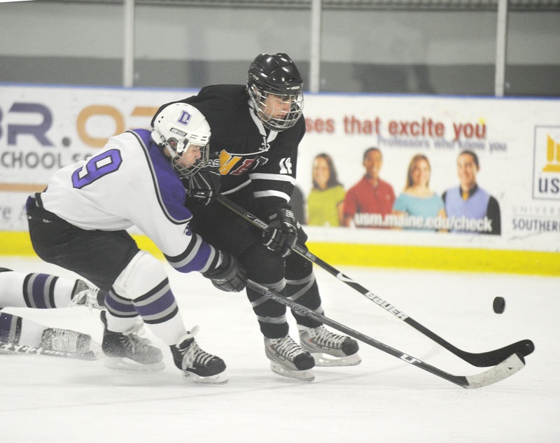 In this January 2010 file photo, Monday, former Deering High School player A.J. Asbury, (No. 9, left), pressures the puck. Deering High School has received a waiver to merge with Portland High School for boys hockey.