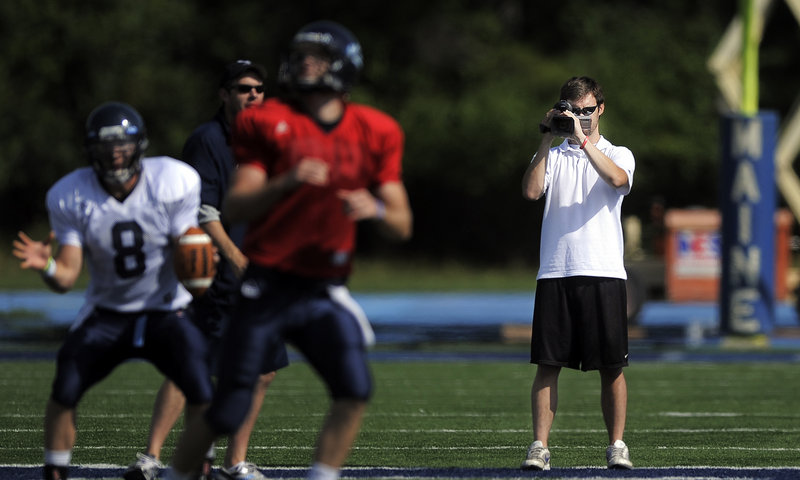 Jimmy Bump, a former Cape Elizabeth quarterback, films the University of Maine football team’s recent practice at Morse Field in Orono.