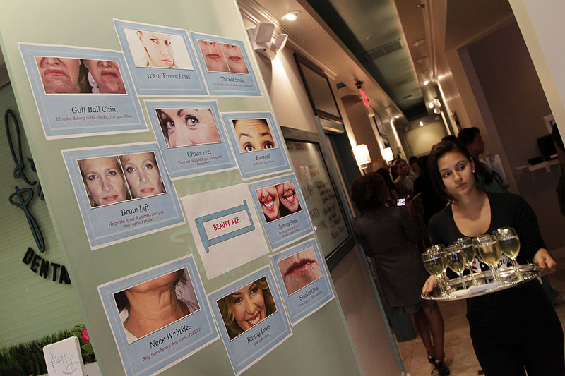 Cosmetic procedures are posted on the door as wine is served during an open house this month at Dr. Patty’s Dental Boutique in Fort Lauderdale, Fla. Dr. April Patterson’s business offers everything from conventional dentistry to injections and chemical peels.